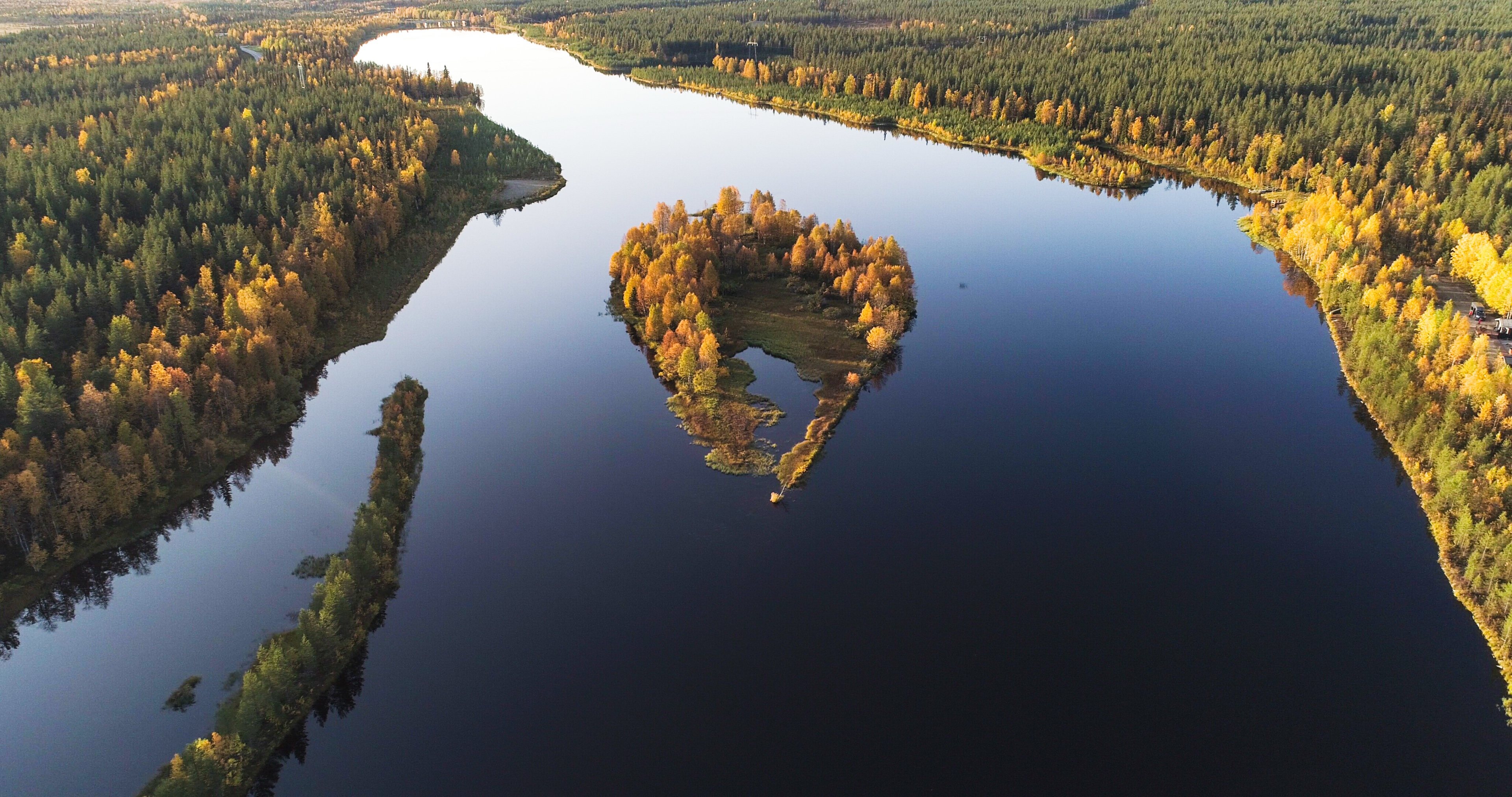 An island in autumn colors on a calm lake, seen from above