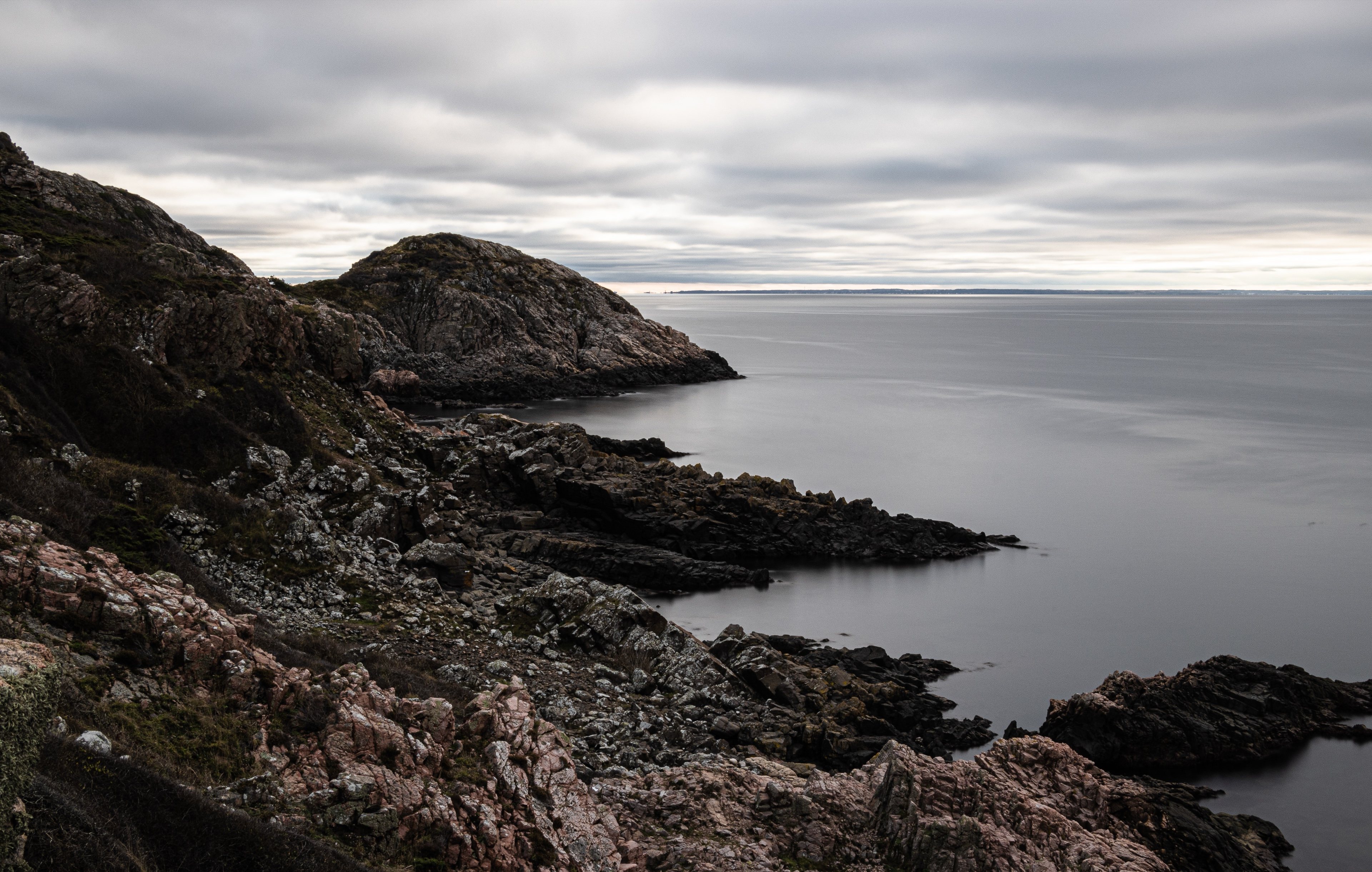 A rocky shore and a calm sea on a gloomy day