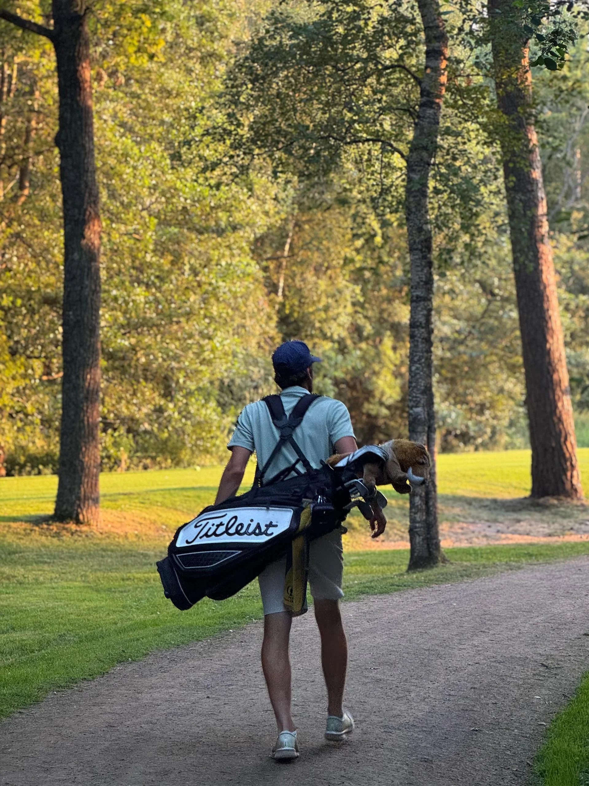 Anton on a golf course, carrying his golf bag
