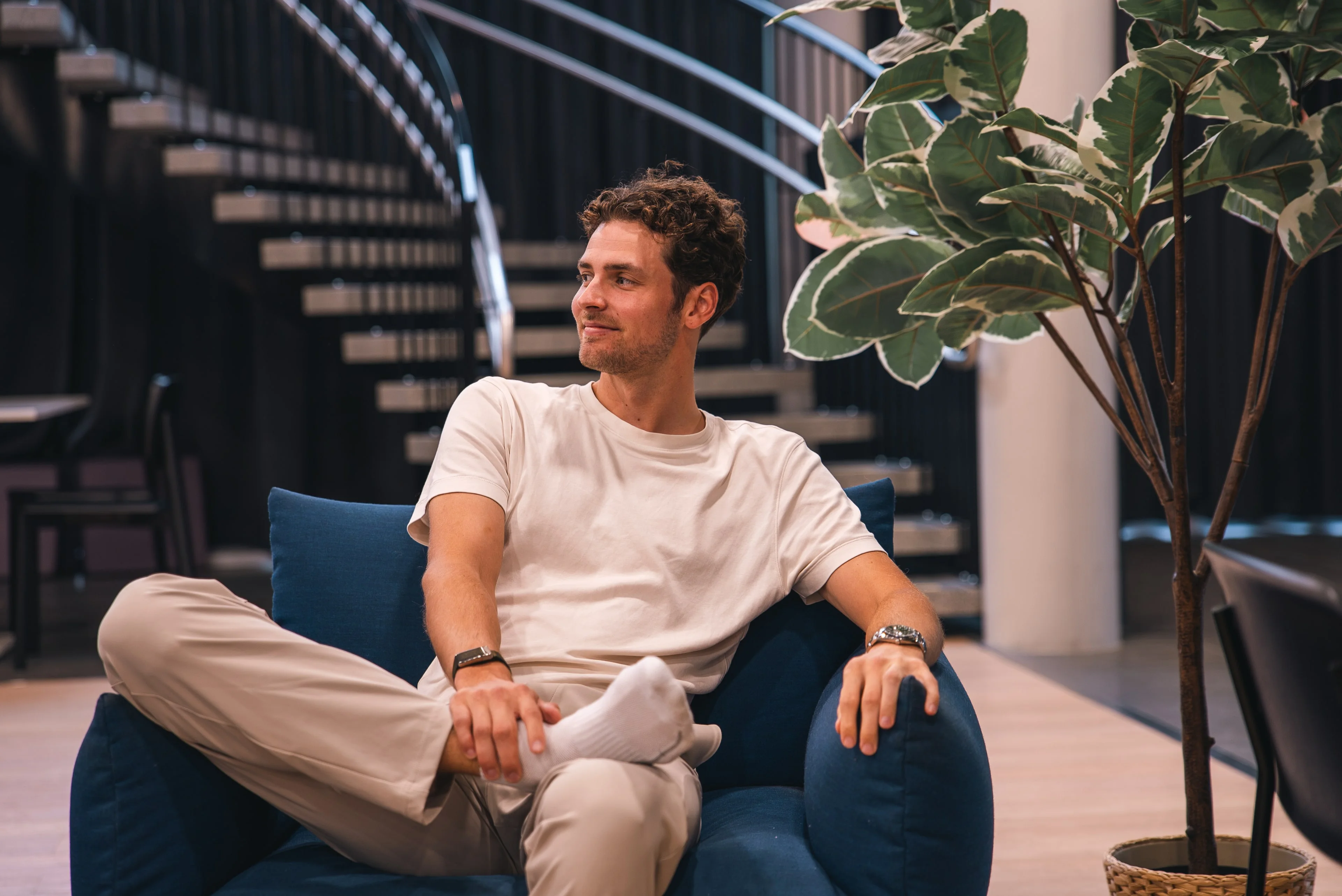 A member of the Innovila team in an armchair in the office lobby, looking to the side