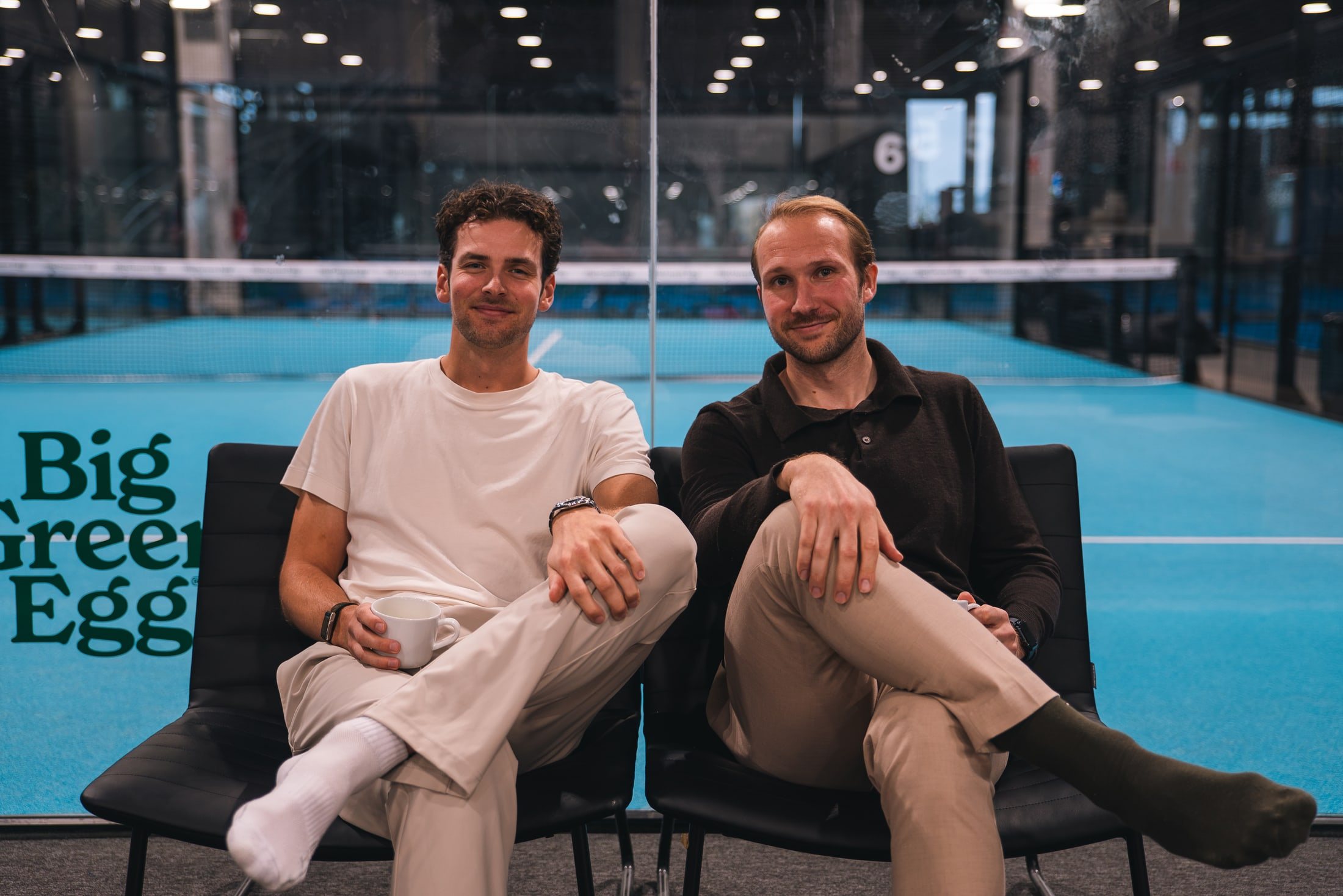 Two members of the Innovila team sitting courtside at a padel hall