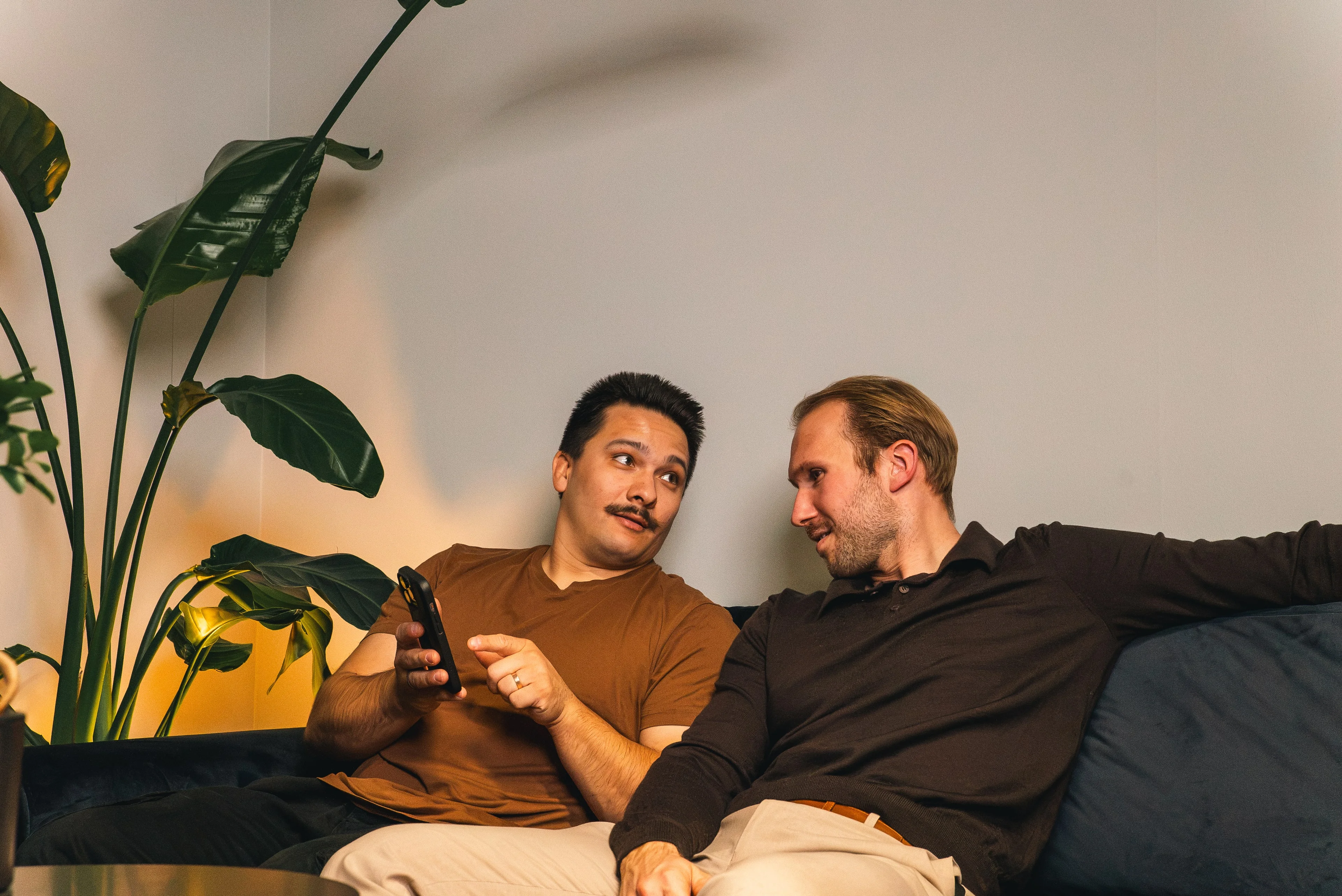 Two members of the Innovila team talking on a sofa, one showing his phone
