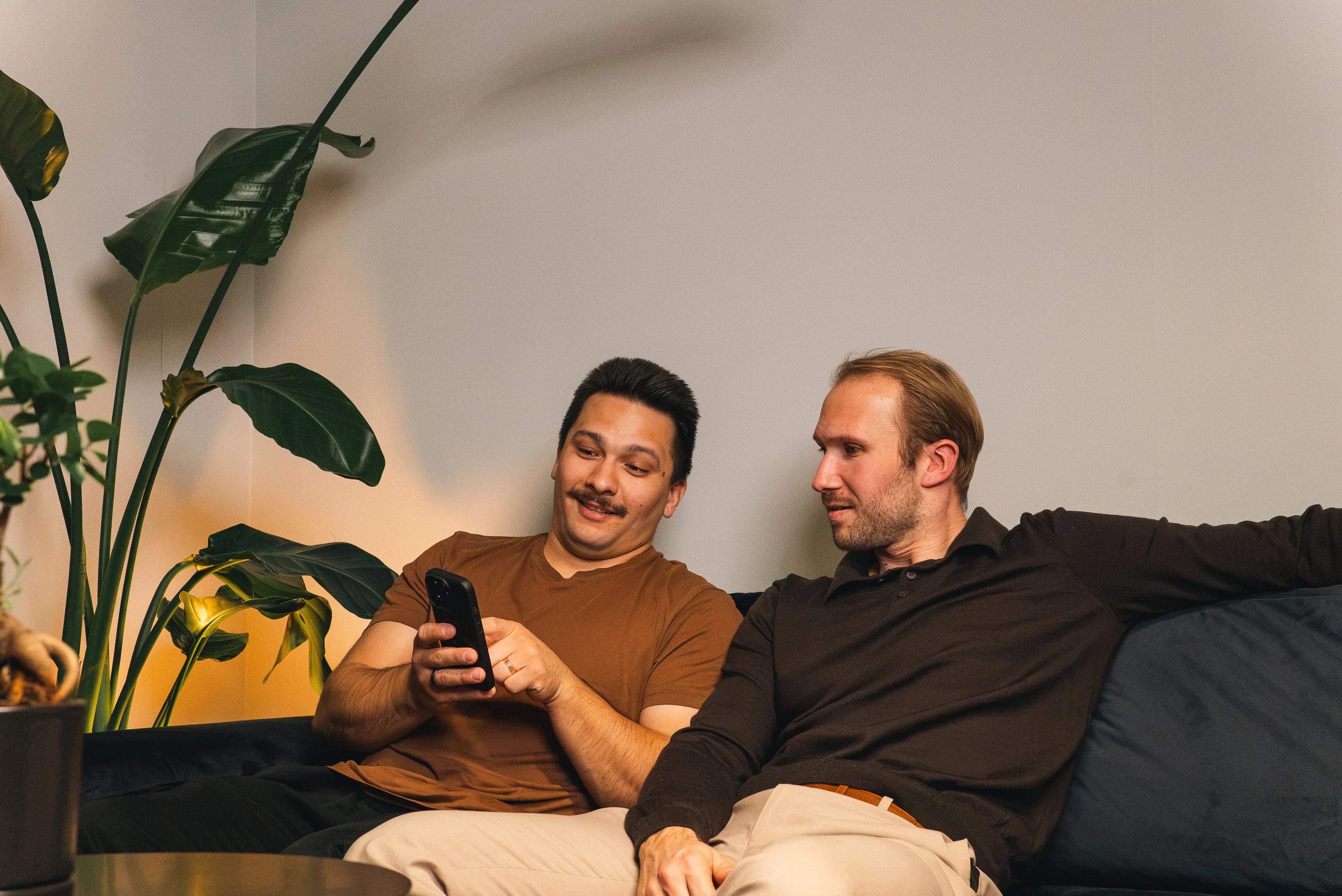 Two members of the Innovila team looking at a phone together on a sofa